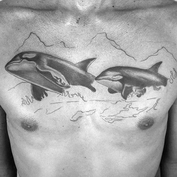 Black and gray tattoo on the chest, featuring two orcas swimming with delicate shading and subtle details, evoking a sense of movement and freedom.