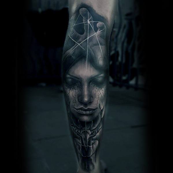 Dark surreal puppet tattoo featuring a calm female face beneath a large hand with strings, symbolizing mental control and inner turmoil.