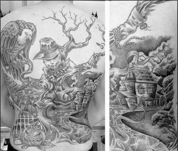 Full back scarecrow tattoo with a haunted house, jack-o'-lantern, eerie trees, flying witch, and crows in a dramatic black and grey style.
