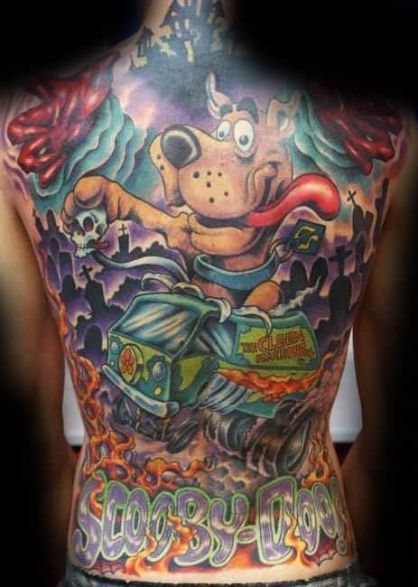 Full back tattoo of Scooby-Doo holding a skull above the Mystery Machine, driving through a graveyard with flames and eerie skies.
