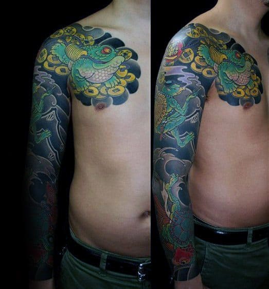 Japanese-style full-sleeve and chest tattoo featuring a green frog sitting on gold coins, surrounded by dark swirling clouds and traditional patterns.