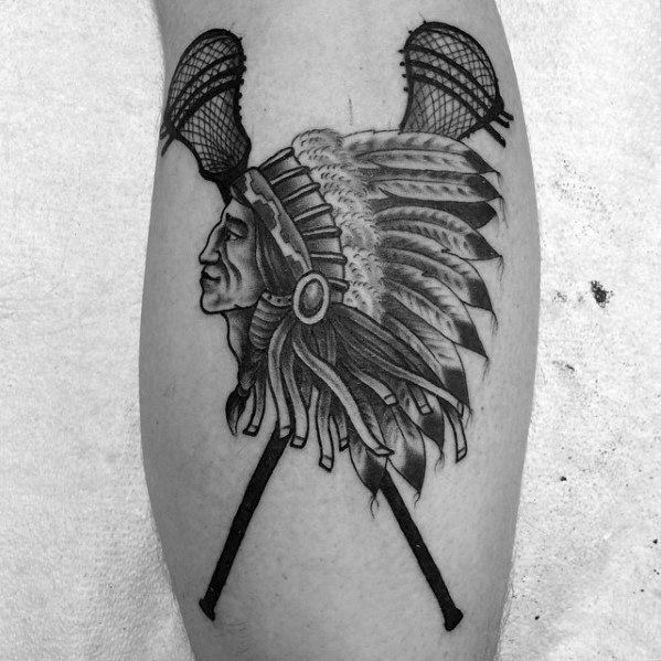 Black and grey lacrosse tattoo featuring a Native American chief in a detailed headdress with crossed lacrosse sticks, symbolizing heritage and sport.