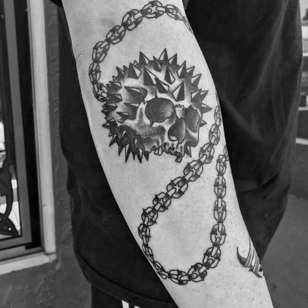 Black and gray mace tattoo featuring a spiked ball fused with a skull, connected by a detailed chain, symbolizing power, mortality, and strength.