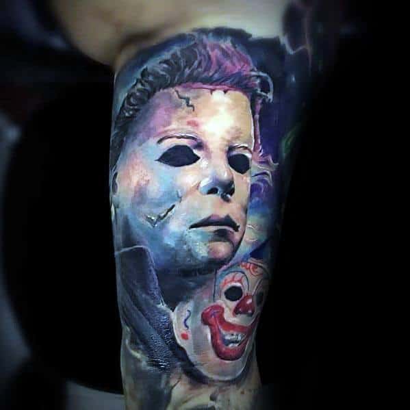 Colorful Michael Myers tattoo featuring his iconic mask with eerie lighting and a sinister clown mask for a haunting horror design.