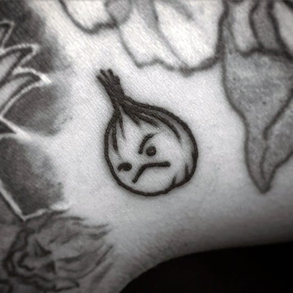 Small black ink tattoo of a simple cartoon-style onion with an angry face, featuring bold outlines and a minimalist design.