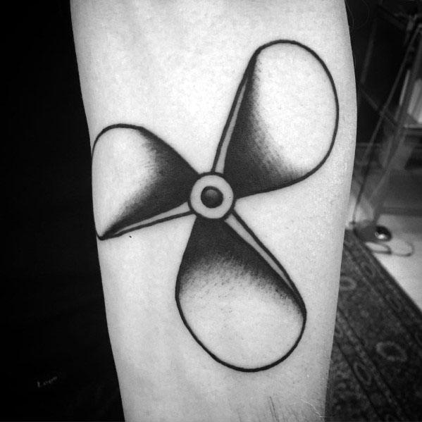 Bold black and grey forearm tattoo of a three-blade propeller with smooth shading and thick outlines for a striking mechanical design.