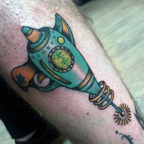 Colorful retro ray gun tattoo with a futuristic design, featuring green and gold tones, sci-fi details, and an energy pulse gauge for a vintage look.