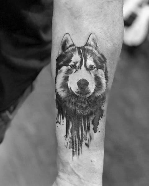 Black and gray Siberian Husky tattoo on a man's forearm, featuring a bold dripping ink effect for a unique artistic touch.