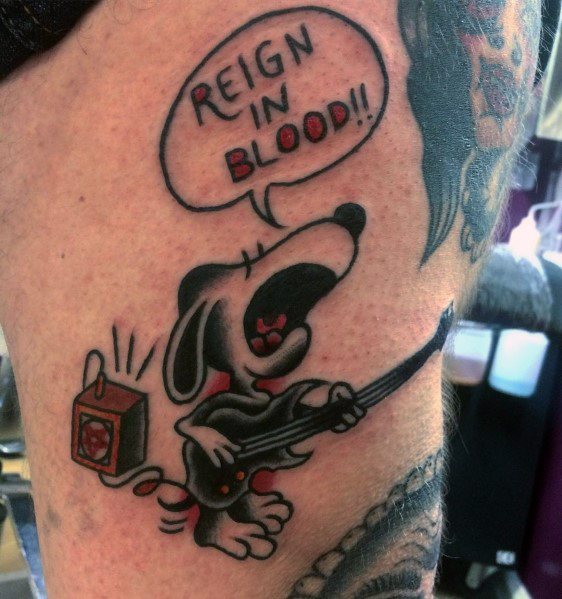 Colorful tattoo of Snoopy dressed in black, playing an electric guitar, shouting "Reign in Blood!!" in a speech bubble, with an amplifier nearby.