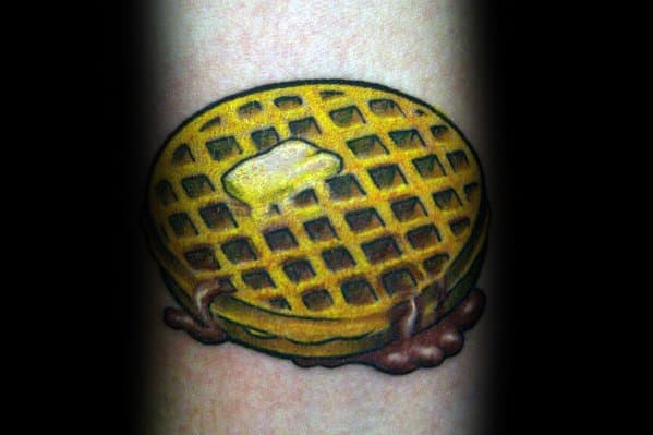 Realistic waffle tattoo with melted butter and dripping syrup, featuring bold shading and rich golden tones for a classic breakfast-inspired design.