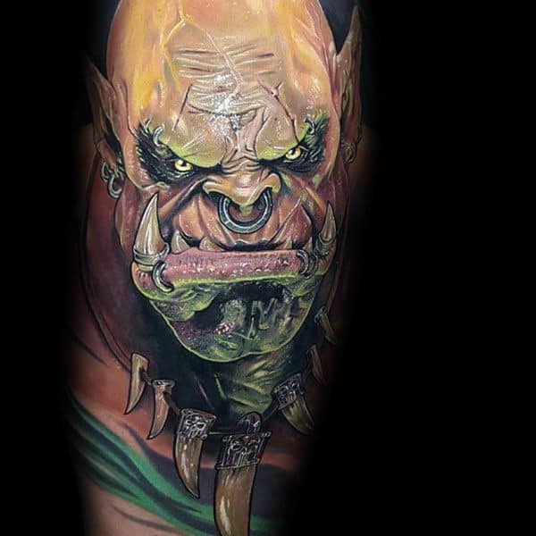 Realistic tattoo of a fierce orc from World of Warcraft, featuring glowing yellow eyes, sharp tusks, and tribal armor, inked with vibrant colors.