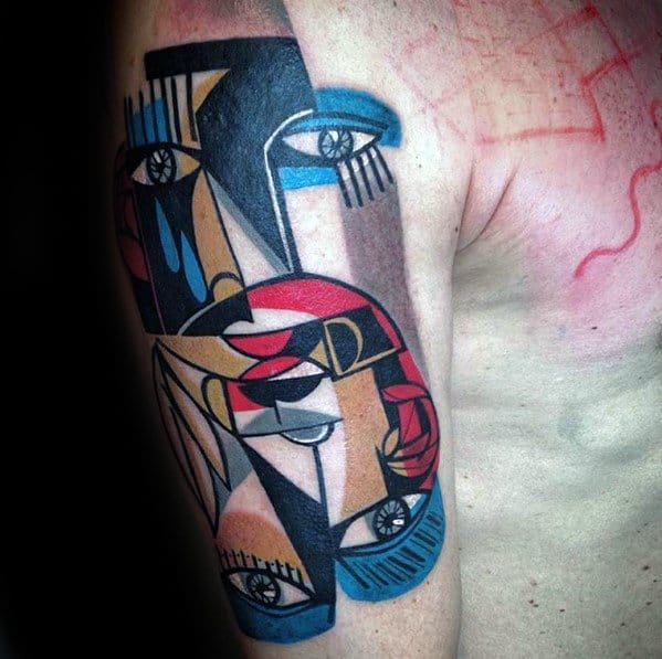 Cubist upper arm tattoo featuring layered abstract faces, eyes, and bold shapes in red, blue, beige, black, and white tones.