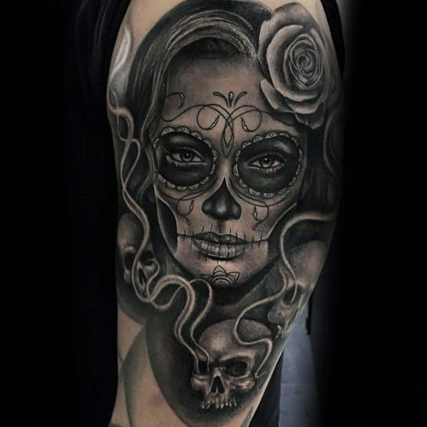 La Catrina tattoo of a woman with sugar skull makeup, a rose in her hair, and smoke forming into a skull in a dark, detailed style.