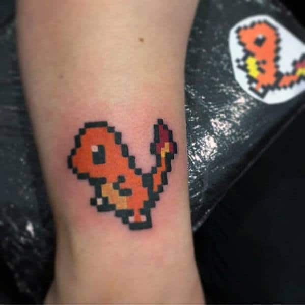 Pixelated Charmander tattoo on forearm in classic 8-bit style, featuring bold black edges and a small red flame on the tail.