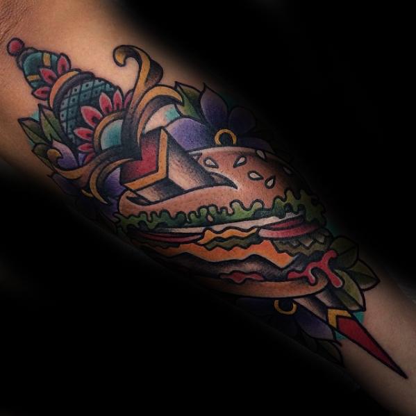 Colorful cheeseburger tattoo in a bold, traditional design with lettuce, cheese, and vibrant floral accents