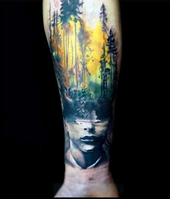 Surreal tattoo of a woman's face merging into a colorful forest landscape, symbolizing a deep connection between nature and the subconscious.