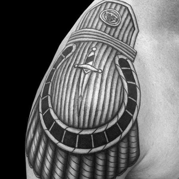 Detailed epaulette tattoo with a vertical-lined texture, central sword emblem, and layered shoulder armor pattern.