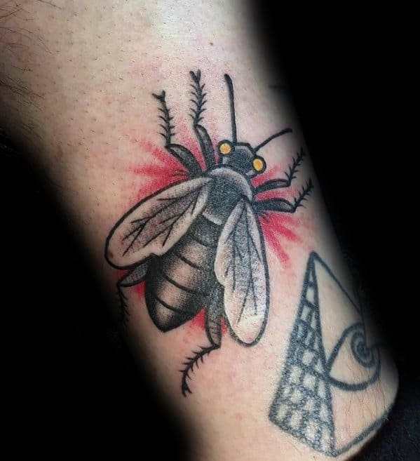 Traditional-style fly tattoo with bold black lines, yellow eyes, and red shading around the wings for a classic, striking effect.