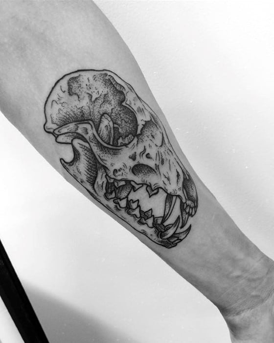 Detailed black and grey tattoo of a fox skull with open jaws, placed on the forearm and featuring fine shading and texture.