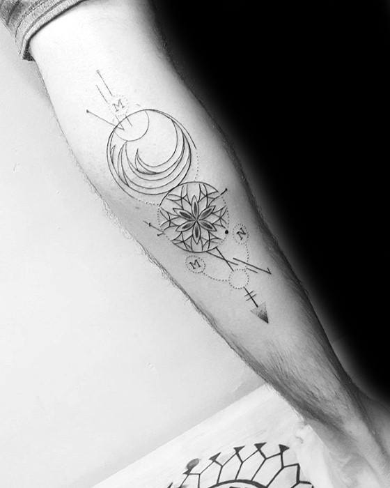 Geometric arrow tattoo with a crescent moon, mandala pattern, dotted lines, and compass-inspired symbols on the forearm.