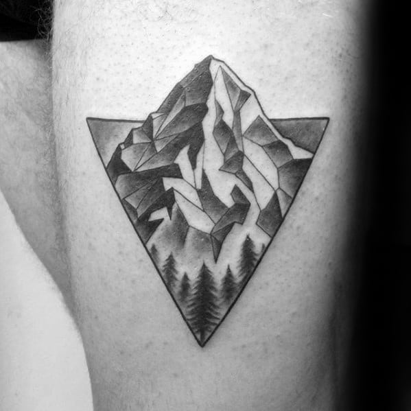Geometric mountain tattoo in a downward triangle with bold angular shading and pine trees at the base for a modern nature look.