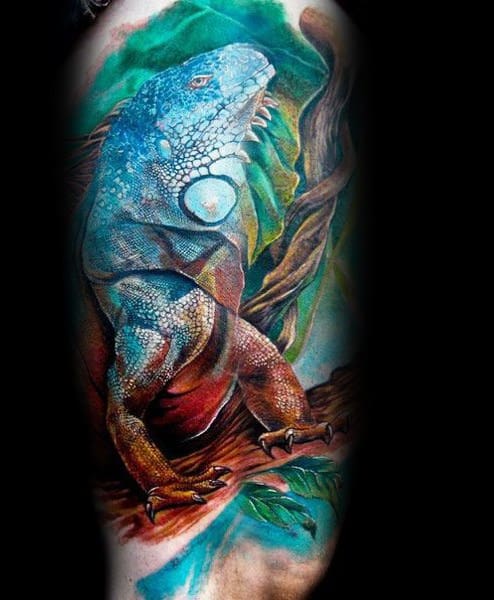 Highly detailed iguana tattoo in blue and orange tones, perched on a twisted branch with vibrant leaves and sky background.