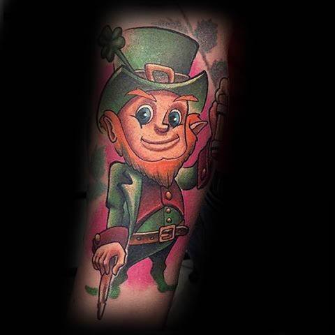 Colorful cartoon-style leprechaun tattoo with bright eyes, green outfit, and a playful stance holding a shamrock and pointing finger.