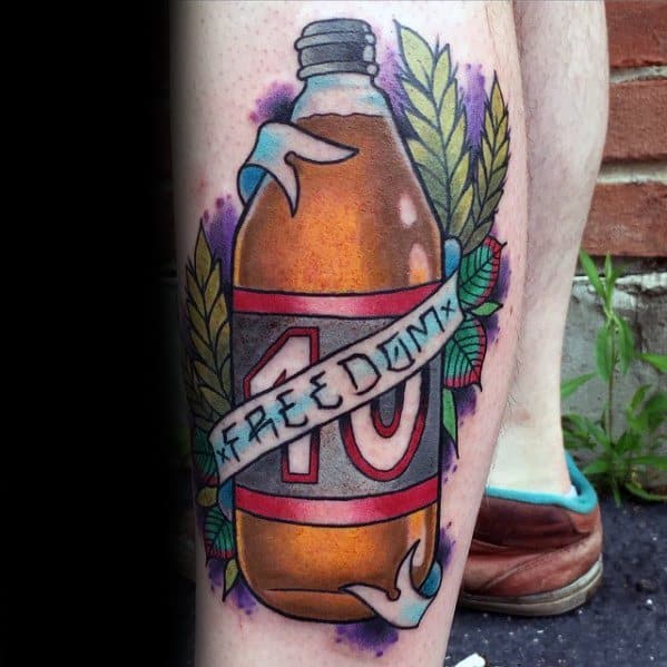 Vibrant leg tattoo of a 40 oz. bottle with a banner reading “Freedom,” surrounded by leaves and purple shading.
