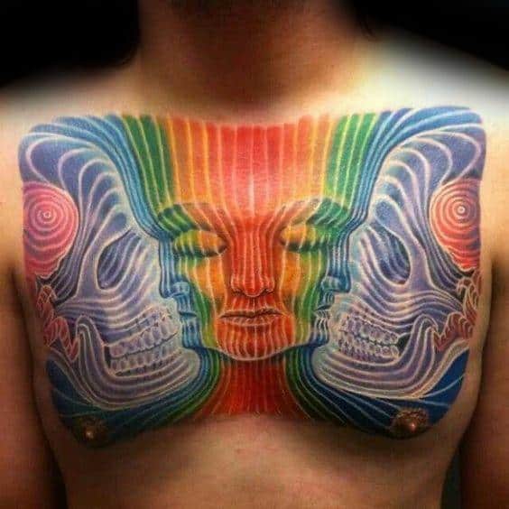 Psychedelic chest tattoo with rainbow-colored linework forming mirrored skulls and a serene central face in a hypnotic pattern.