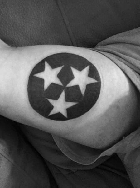 Black and grey Tennessee three-star emblem tattoo on the arm, featuring a bold circular design symbolizing state pride and unity.