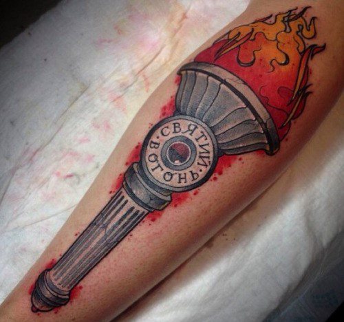 Realistic torch tattoo with bright flames and Cyrillic script on the handle, surrounded by red ink splatter details.