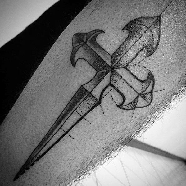 Intricate black ink tattoo of a cross shaped like a dagger, with fine dotwork, shading, and geometric detailing on the arm.