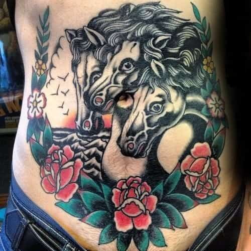 Traditional stomach tattoo with three black horse heads, red and green roses, and a scenic background with birds and waves.