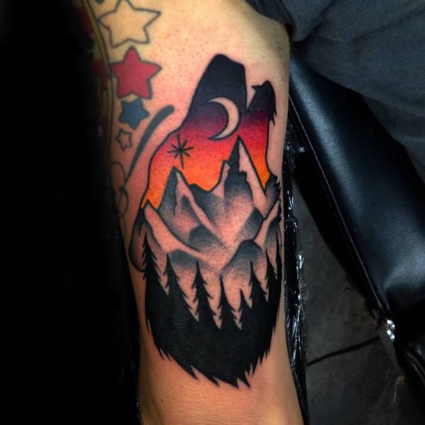 Bold bear-shaped tattoo filled with snowy mountains, pine trees, a crescent moon, and a vivid red-orange night sky.