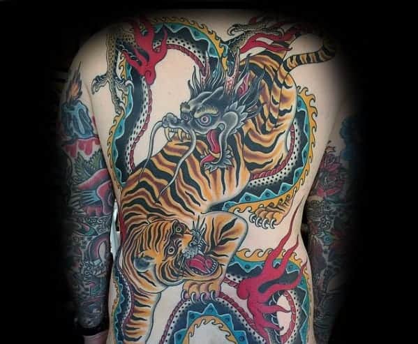 Full back tattoo showcasing a dragon and a tiger locked in a fierce battle