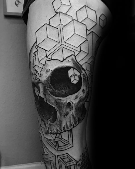 Black and grey thigh tattoo of a realistic skull integrated with geometric 3D cubes, including one cube embedded in the skull's eye socket.