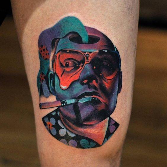 Colorful thigh tattoo of a man with glasses and a cigarette, featuring abstract elements and vivid shading.