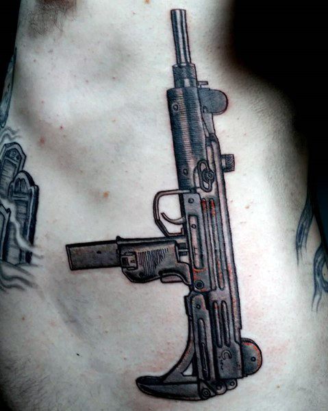 Detailed black and grey Uzi tattoo on the ribcage with fine line shading and realistic firearm design.