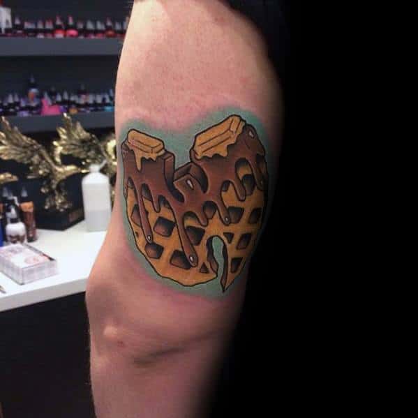 Bold waffle tattoo in the shape of a "W," covered in dripping chocolate syrup and butter, creating a unique and eye-catching breakfast design.