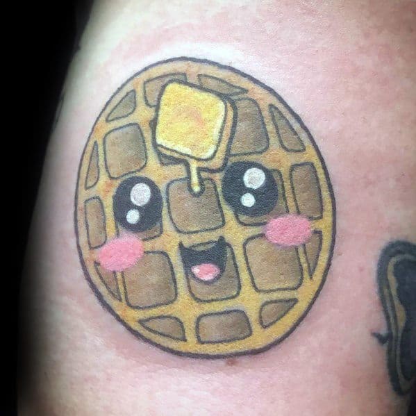 Cute kawaii-style waffle tattoo with a smiling face, rosy cheeks, and a pat of butter on top, giving it a fun and playful breakfast theme.