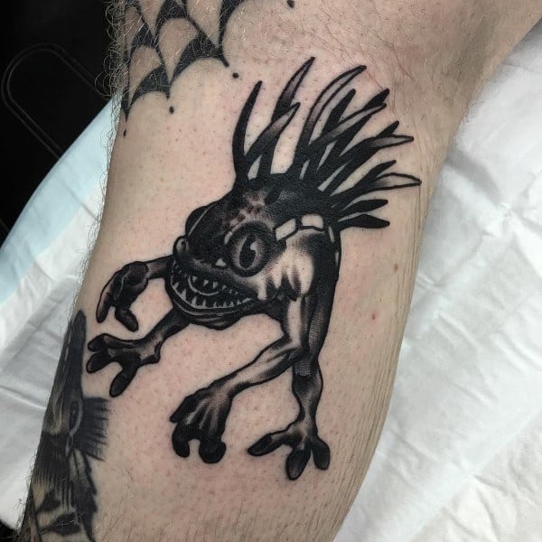 Black ink tattoo of a Murloc from World of Warcraft, featuring bold shading and sharp details, inked on the leg.