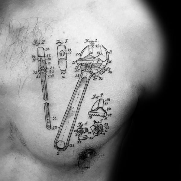 Black ink chest tattoo of a wrench blueprint design, featuring labeled diagrams and mechanical components in a technical sketch style.