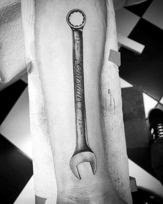 Black and grey tattoo of a 22mm wrench with the word *Antonio* engraved along the handle in elegant script.
