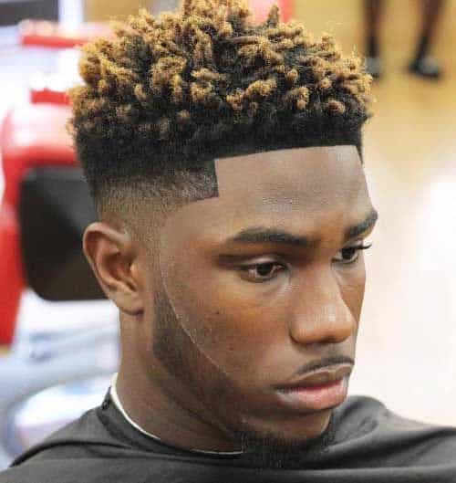 A black man haircut featuring top bleached hair twists with roots maintained black and paired with a low fade