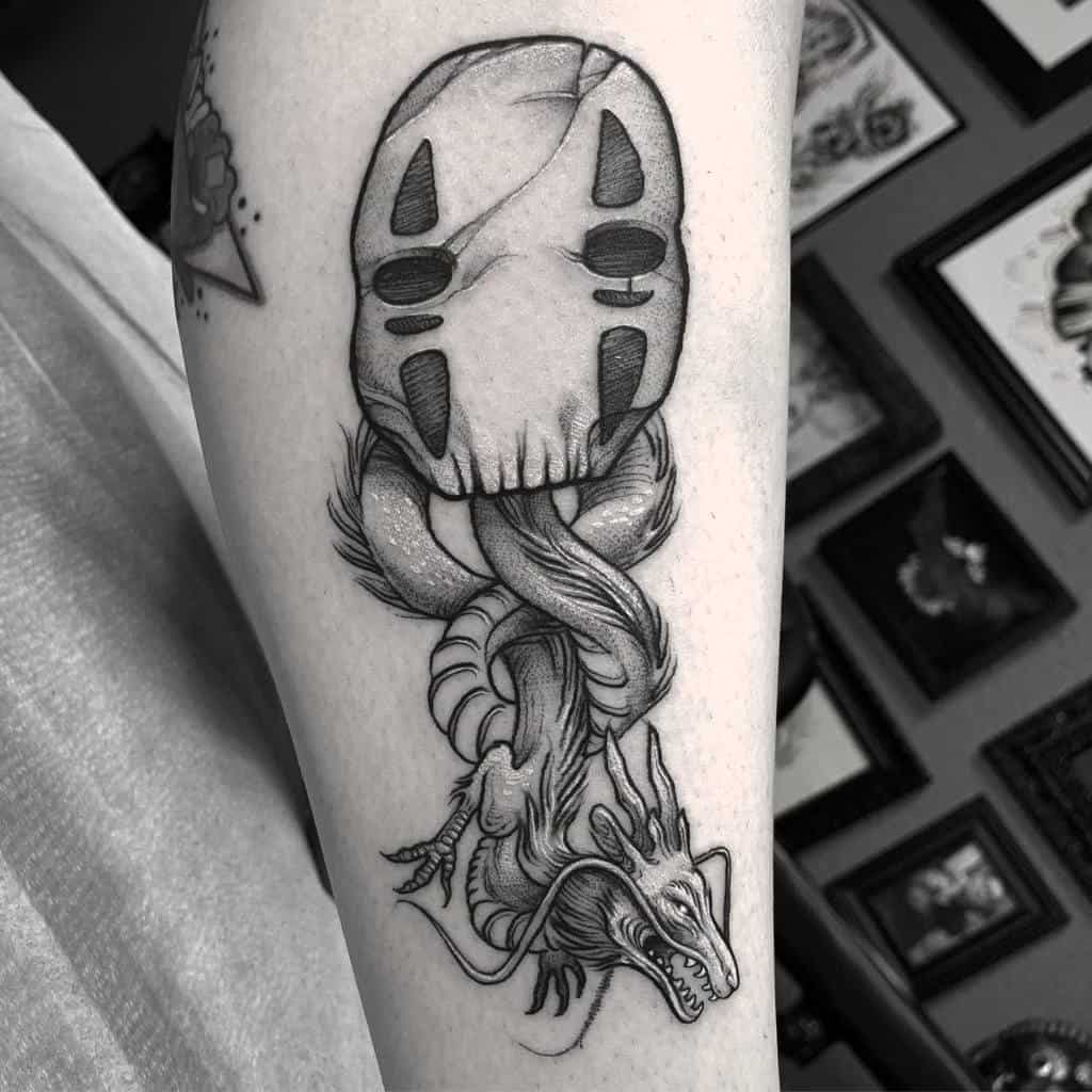 Black and grey tattoo featuring No-Face's mask from Spirited Away, merging into Haku in dragon form with flowing, intricate details