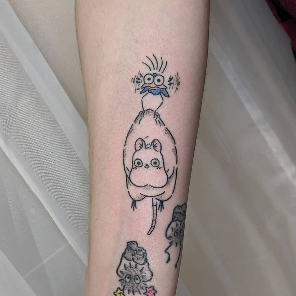 Minimalist tattoo of Boh and Yu-Bird from Spirited Away, featuring fine lines and subtle blue accents, with additional soot sprites below
