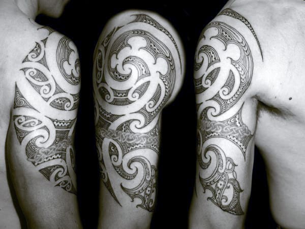Black and white image of intricate tribal tattoos on a person's upper arm and shoulder