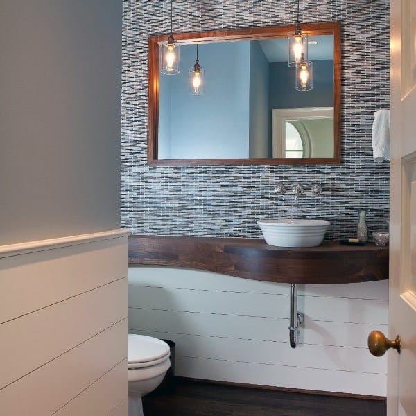 Modern half bath with mosaic wall, wood-framed mirror, pendant lights, vessel sink, and white subway tile accents