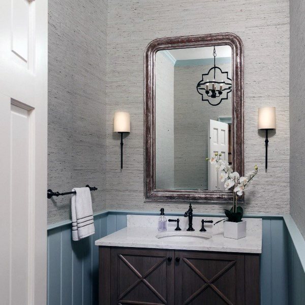 Rustic bathroom with wood vanity, textured wallpaper, and large framed mirror.
