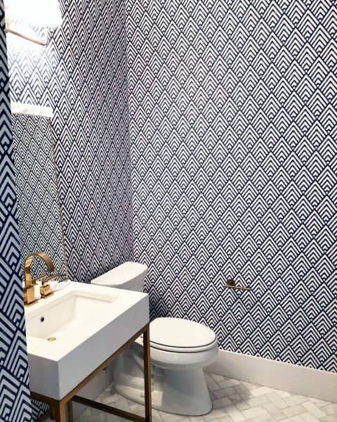 Modern bathroom with blue and white geometric wallpaper and white vanity.